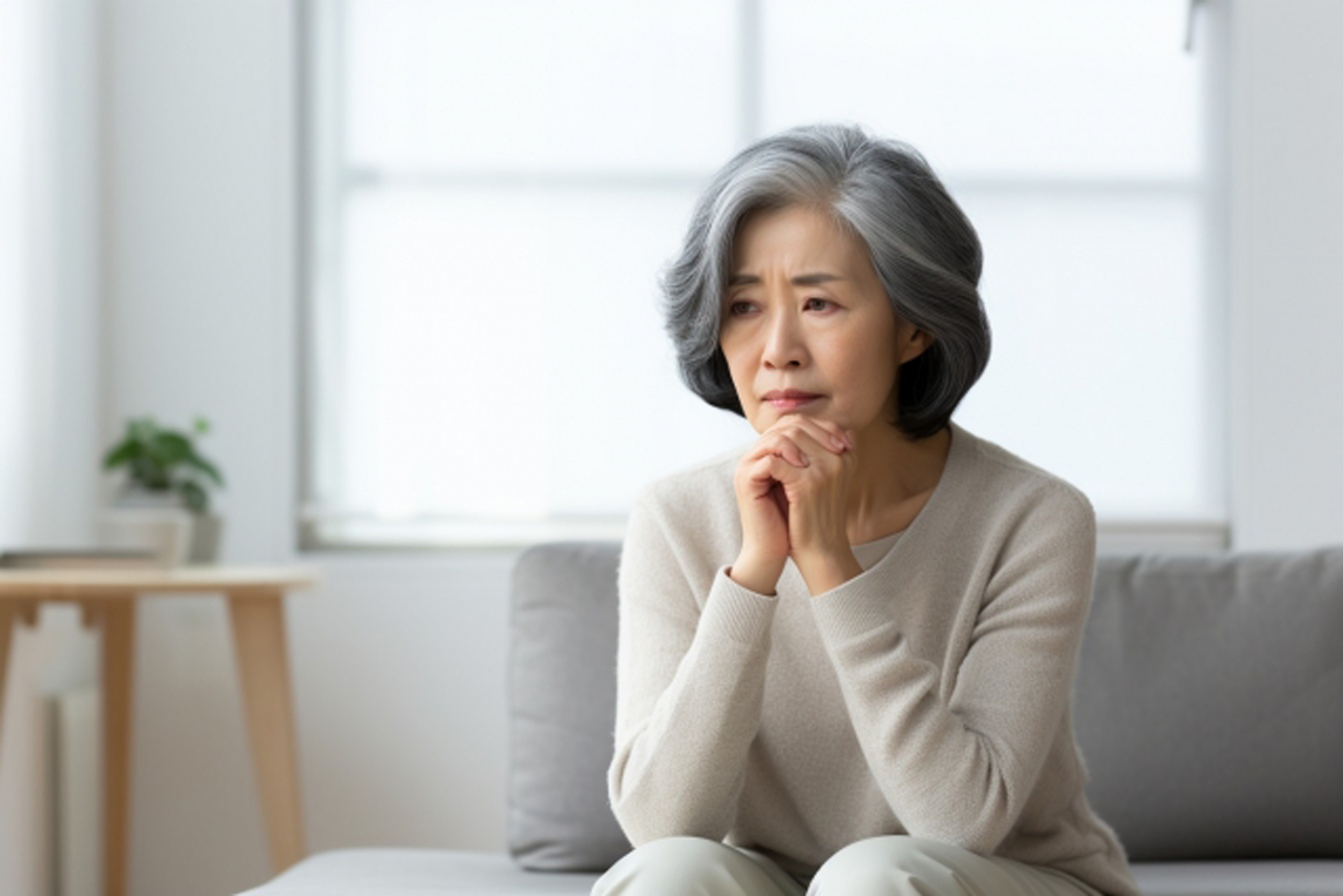 不安げな表情で一点を見つめる高齢者