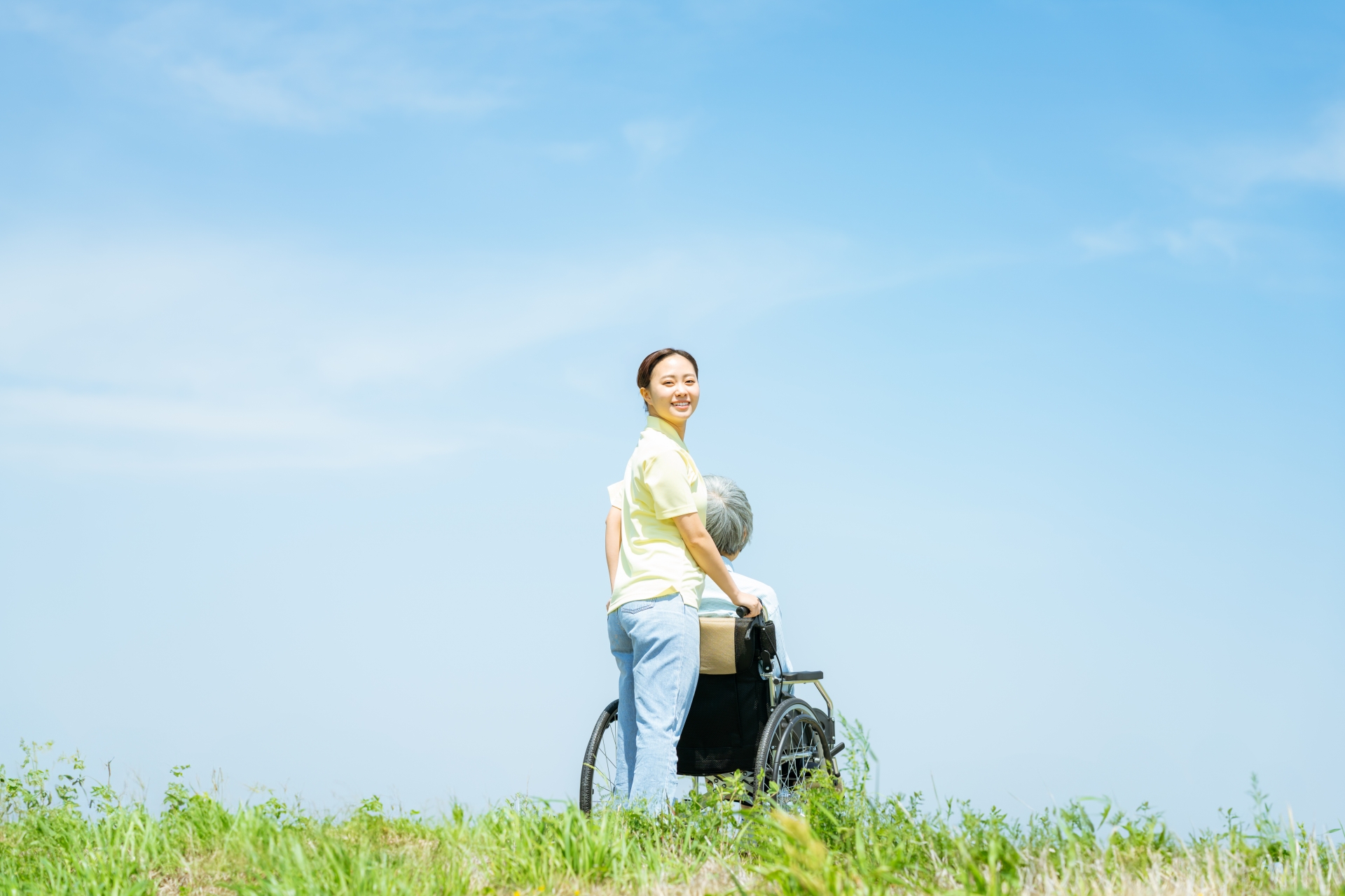晴れやかな表情で車いすを押す介護士の女性